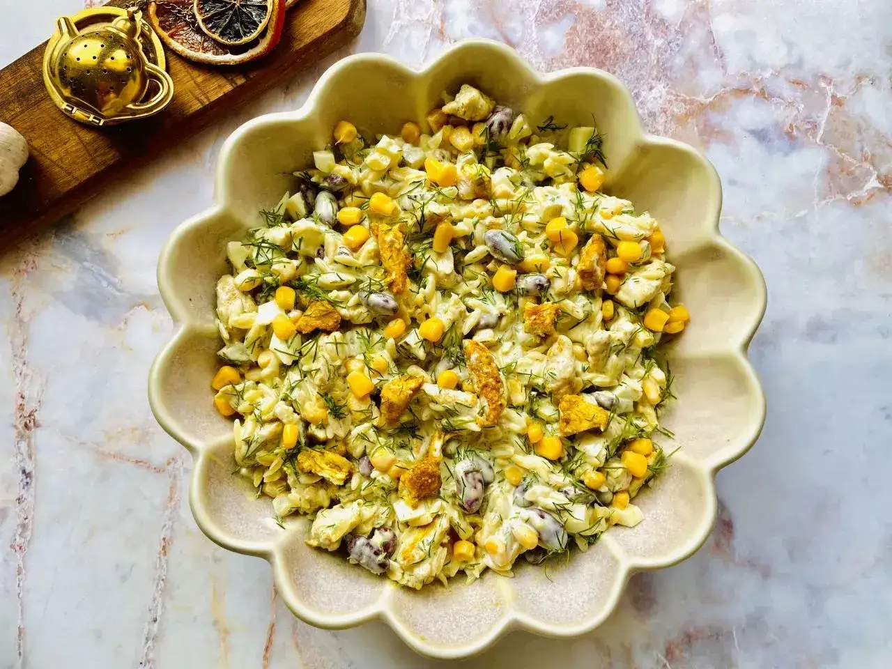 Pyszna sałatka makaron z kurczakiem, kukurydzą i fasolką, udekorowana świeżym koperkiem.