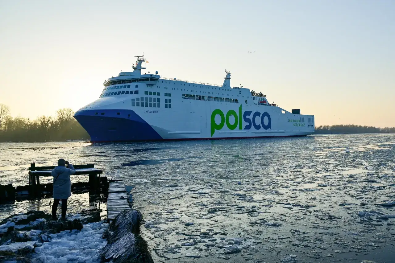 Osoba na pomoście robi zdjęcie promowi 