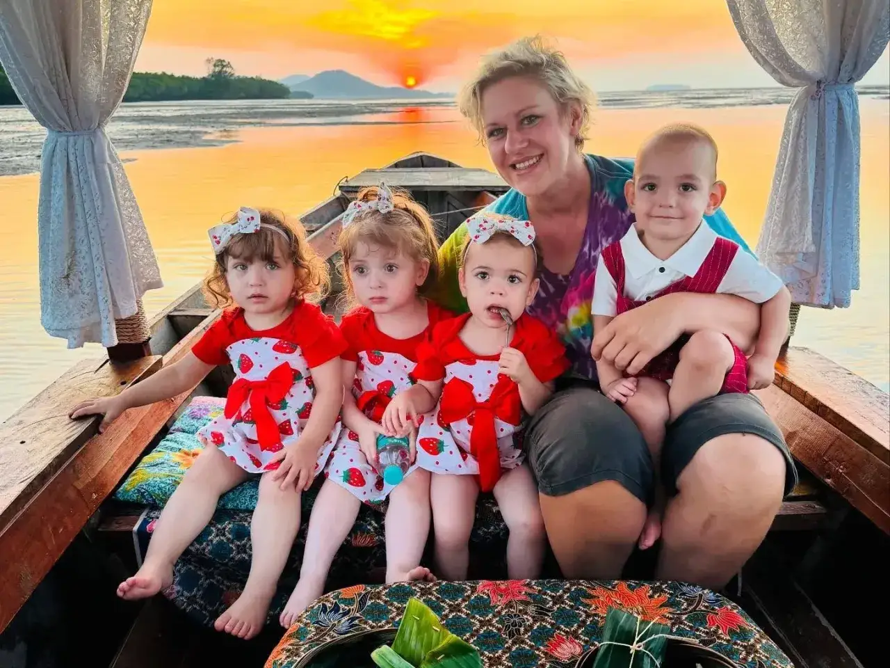 Pięcioraczki z Horyńca w łodzi o zachodzie słońca. Mama z dziećmi w strojach w truskawki.