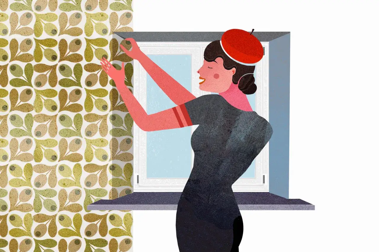 Kobieta w czerwonym beretcie wykonuje tapetowanie przy otworach okiennych i drzwiowych. Wz&oacute;r tapety to oliwki.