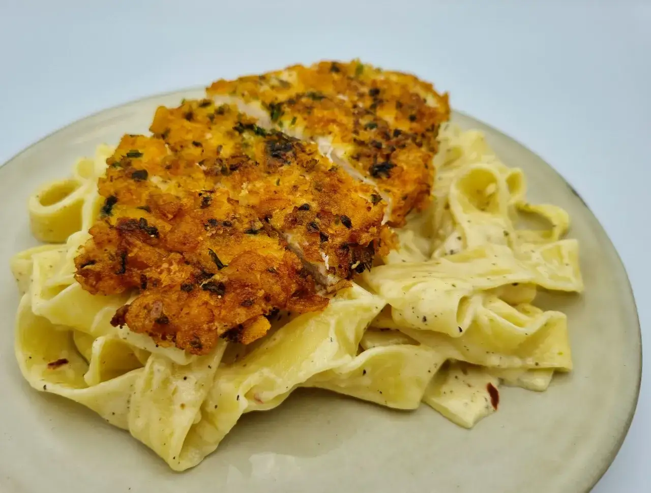 Chrupiący kurczak na kremowym makaronie tagliatelle w sosie alfredo. Idealny przepis na kurczaka alfredo.