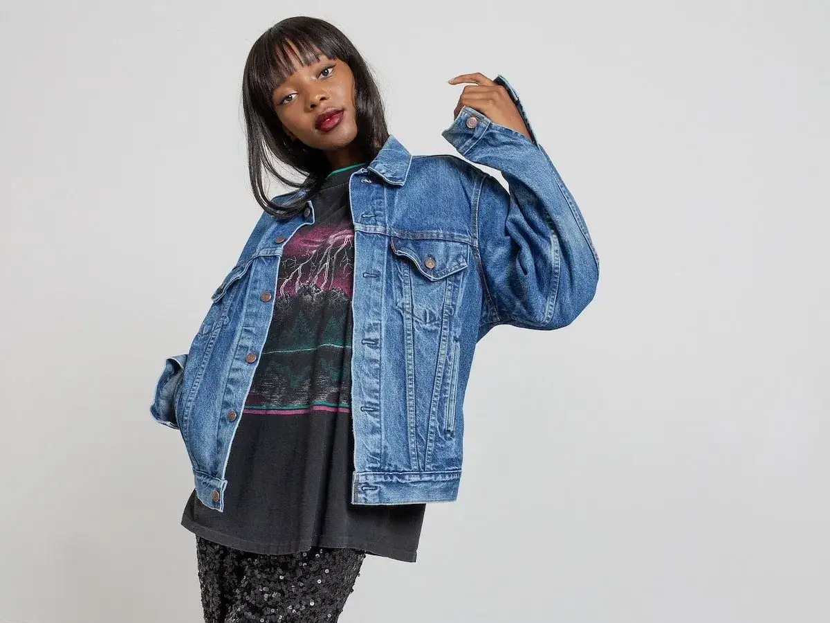 Młoda kobieta w dżinsowej kurtce i błyszczącej spódnicy. Stylizacja pokazuje, co to znaczy vintage – ponadczasowa moda z charakterem.