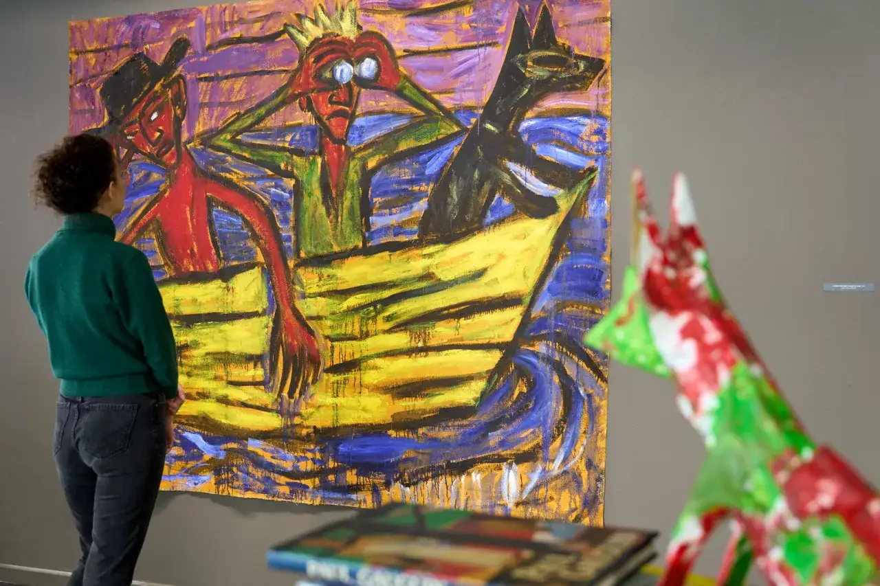 Wrocław wystawa malarstwa: kobieta ogląda ekspresyjny obraz przedstawiający ludzi i psa w łodzi.