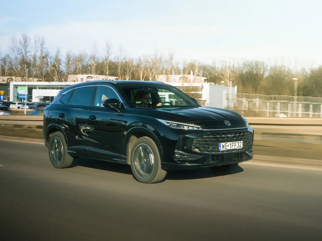 Czarny SUV jedzie po drodze. Kierowca w okularach prowadzi pojazd. Zastanawiasz się, ile pali suv?