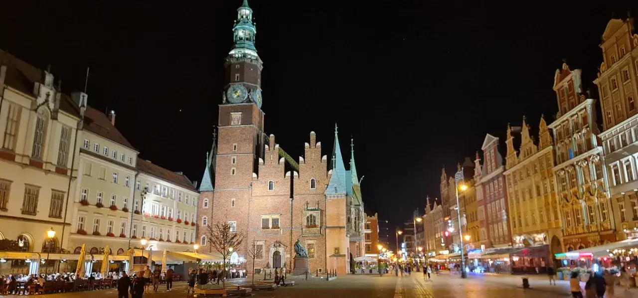 Nocny Rynek we Wrocławiu, z oświetlonym Ratuszem i kamienicami. Idealne miejsce na wieczorne atrakcje dla dorosłych.