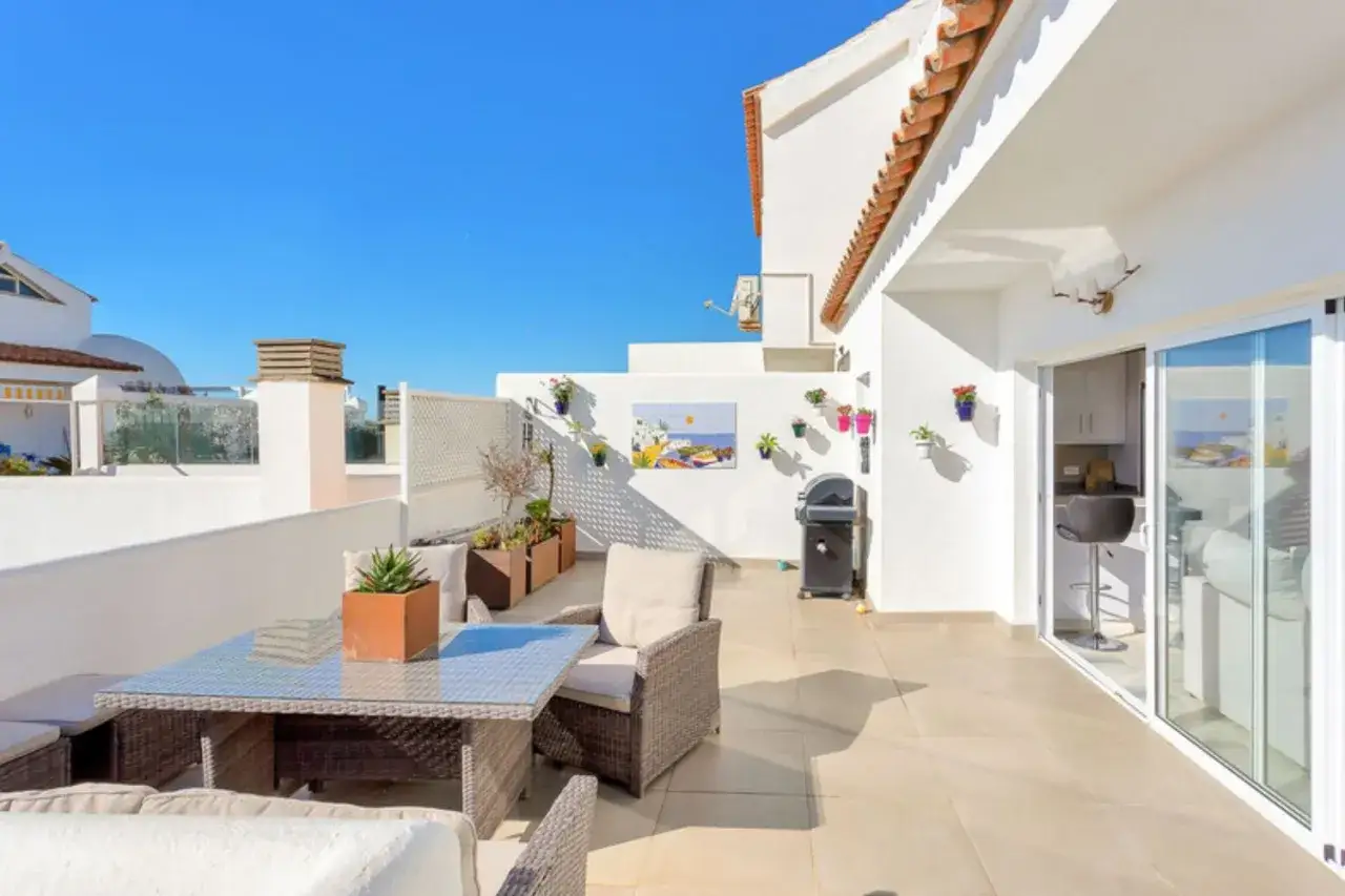 Słoneczny taras z meblami i grillem, idealny do wypoczynku. Zastanawiasz się, ile kosztuje wynajęcie mieszkania w Hiszpanii?