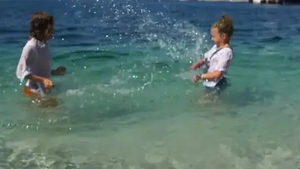 dzieci bawiące się na chorwackiej plaży z butami do wody