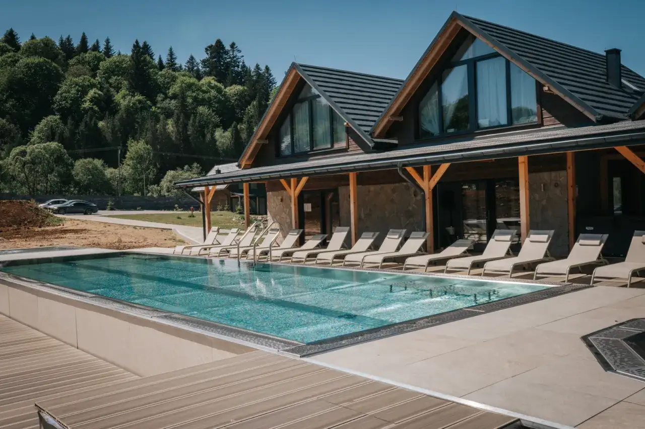 Nowoczesny bieszczady hotel z basenem i leżakami, otoczony zielenią gór.