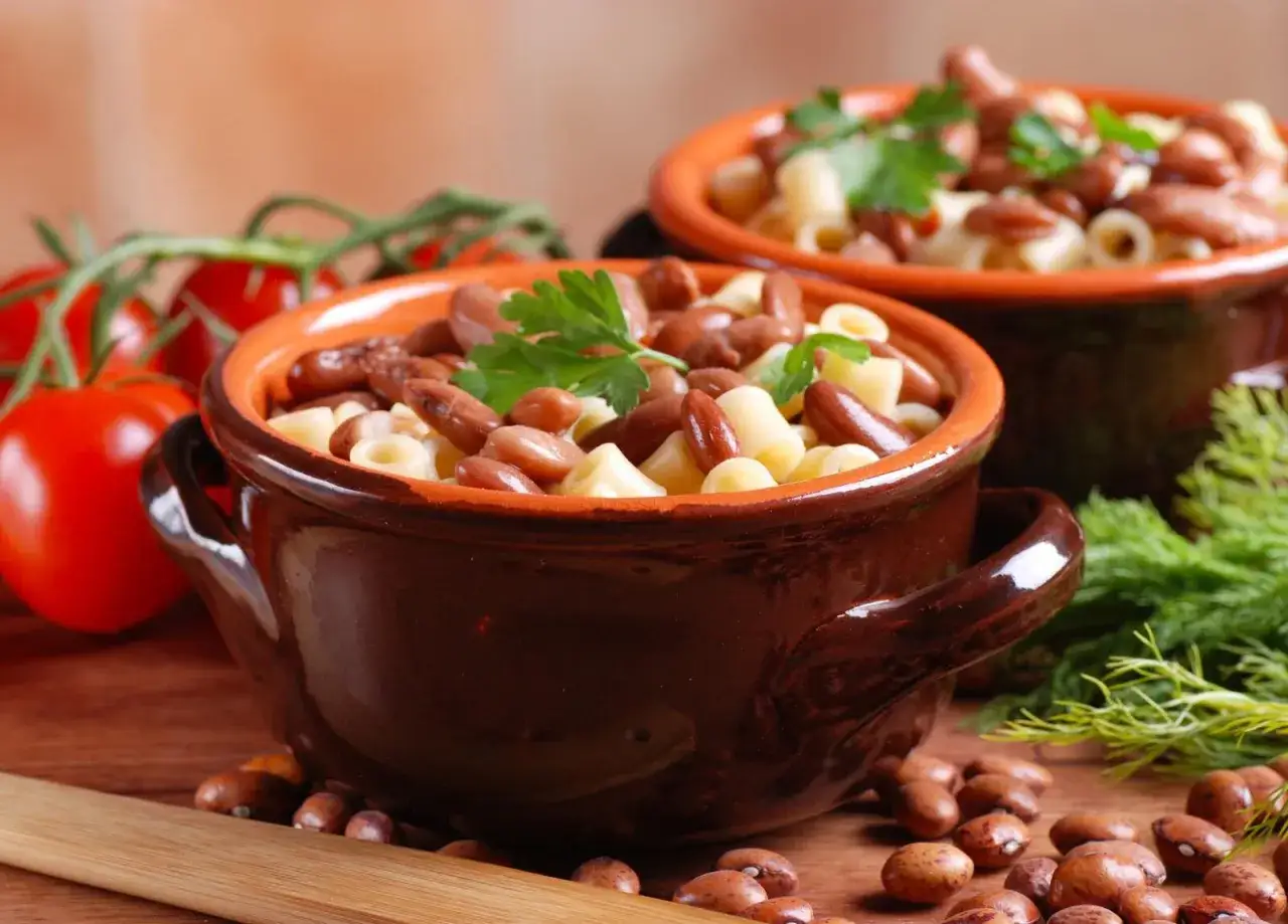 Pyszne Pasta e Fagioli przepis w glinianych miseczkach, z pomidorami i ziołami w tle. Idealne na rozgrzewający posiłek.