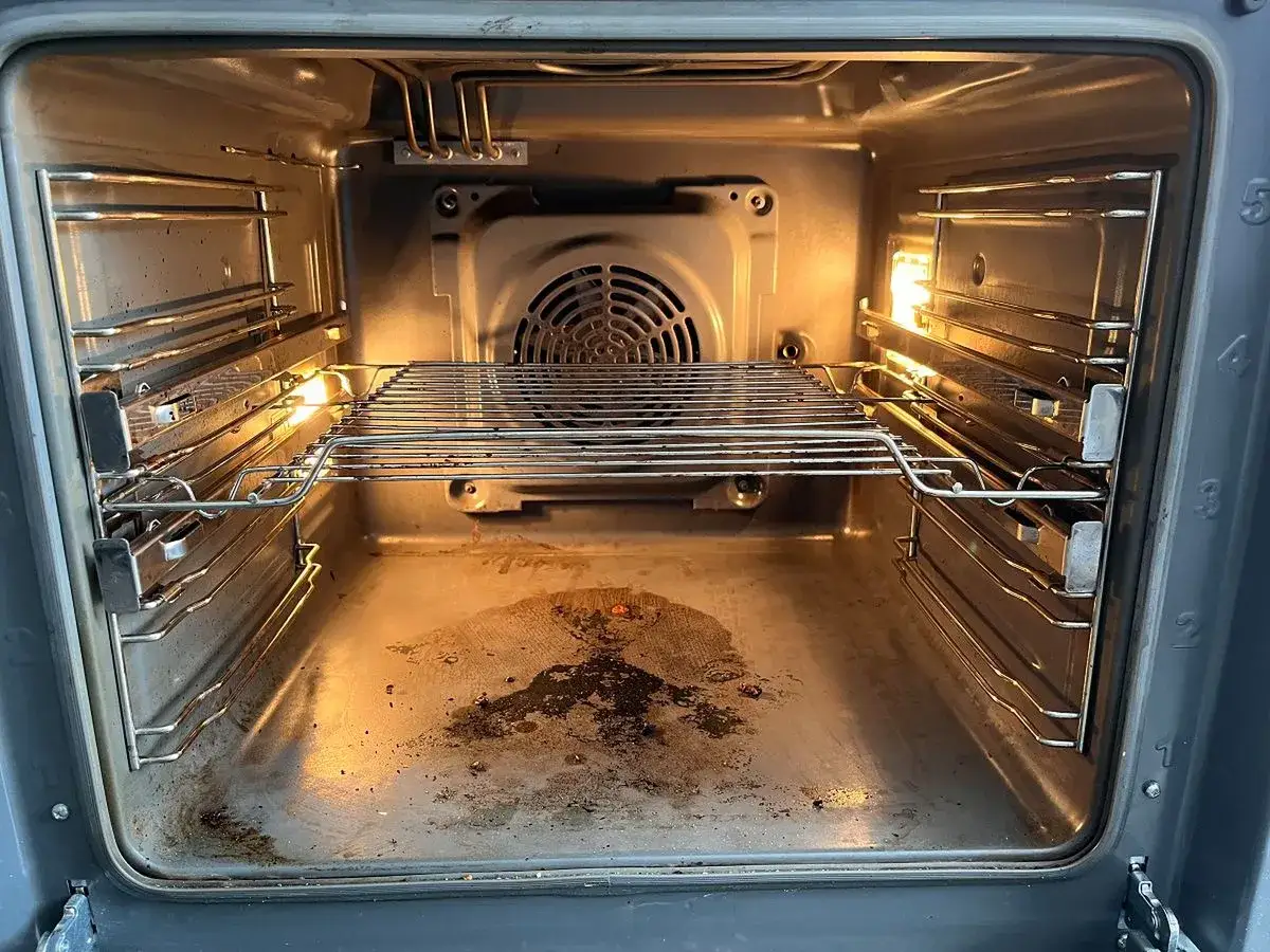 Wnętrze piekarnika z widocznymi śladami przypalonego tłuszczu na dnie. Czas na czyszczenie!