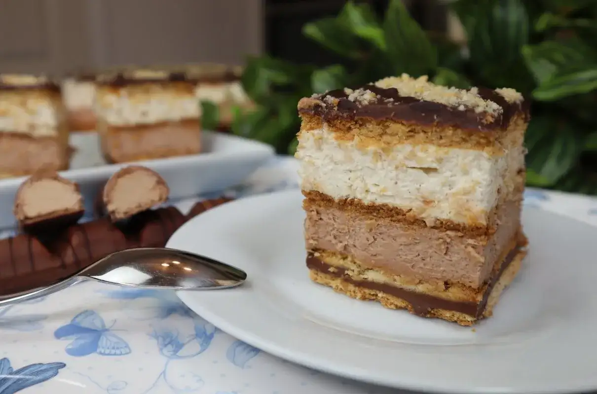 Pyszne ciasto Kinder Bueno z kremem czekoladowym i białą masą, posypane orzechami. Idealne na deser.