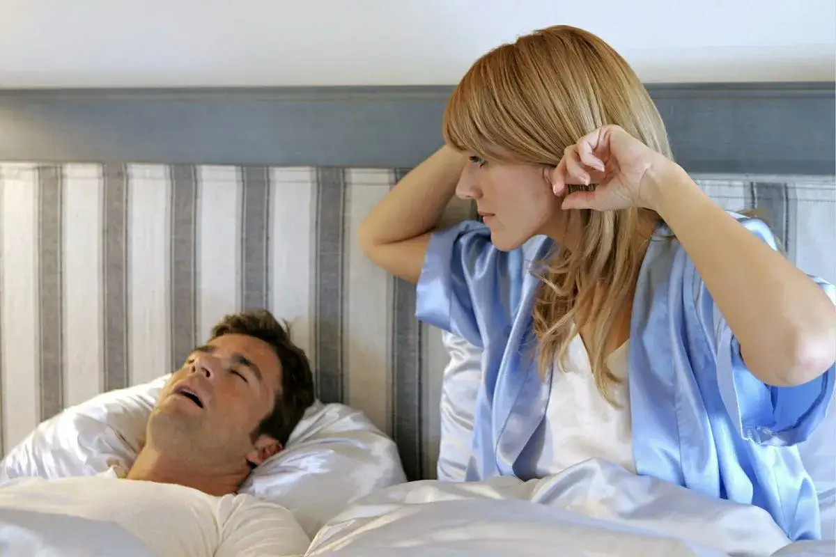 Para śpiąca, jedna osoba chrapie, druga zaniepokojona