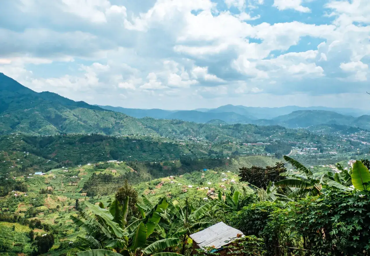 Zielone wzg&oacute;rza i doliny, domy rozsiane po zboczach, tworzą malowniczy krajobraz z Kigali. Chmury na niebie dodają głębi.