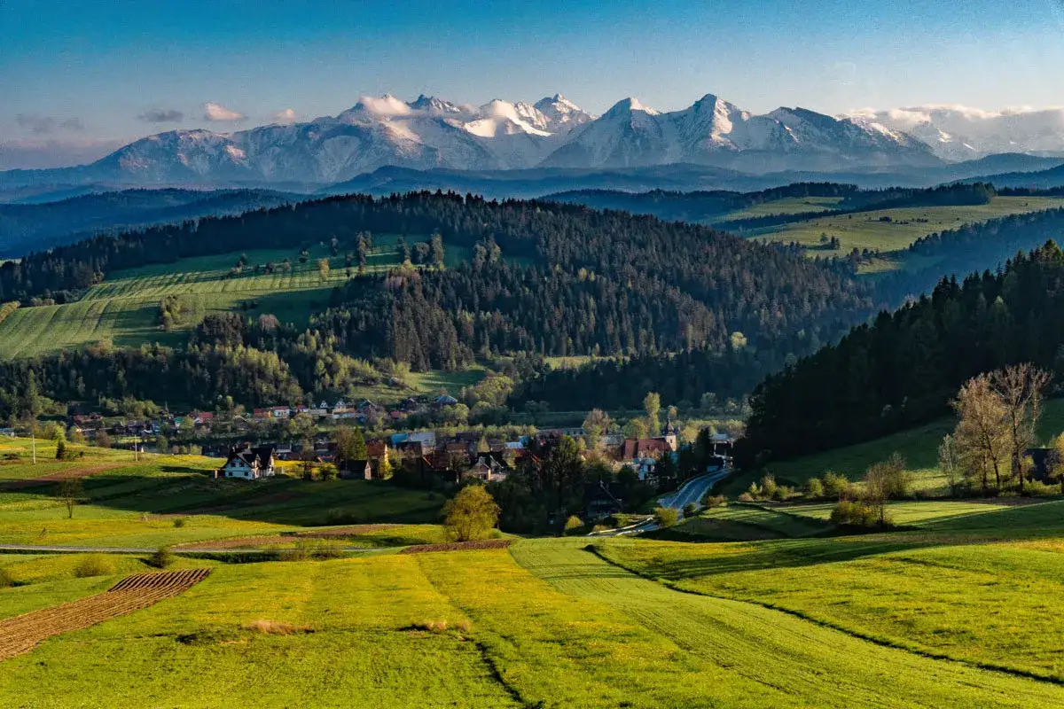 Zielone wzg&oacute;rza, lasy i malownicza wieś pod ośnieżonymi szczytami. Tak właśnie wyglądają Pieniny, gdzie są te cuda natury.