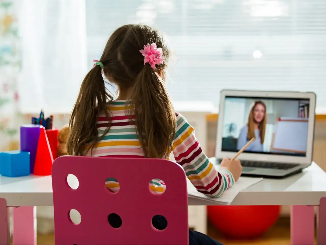Dziewczynka z warkoczykami uczy się zdalnie, korzystając z laptopa. To świetny przykład, jak zacząć edukację domową, łącząc się z nauczycielem online.