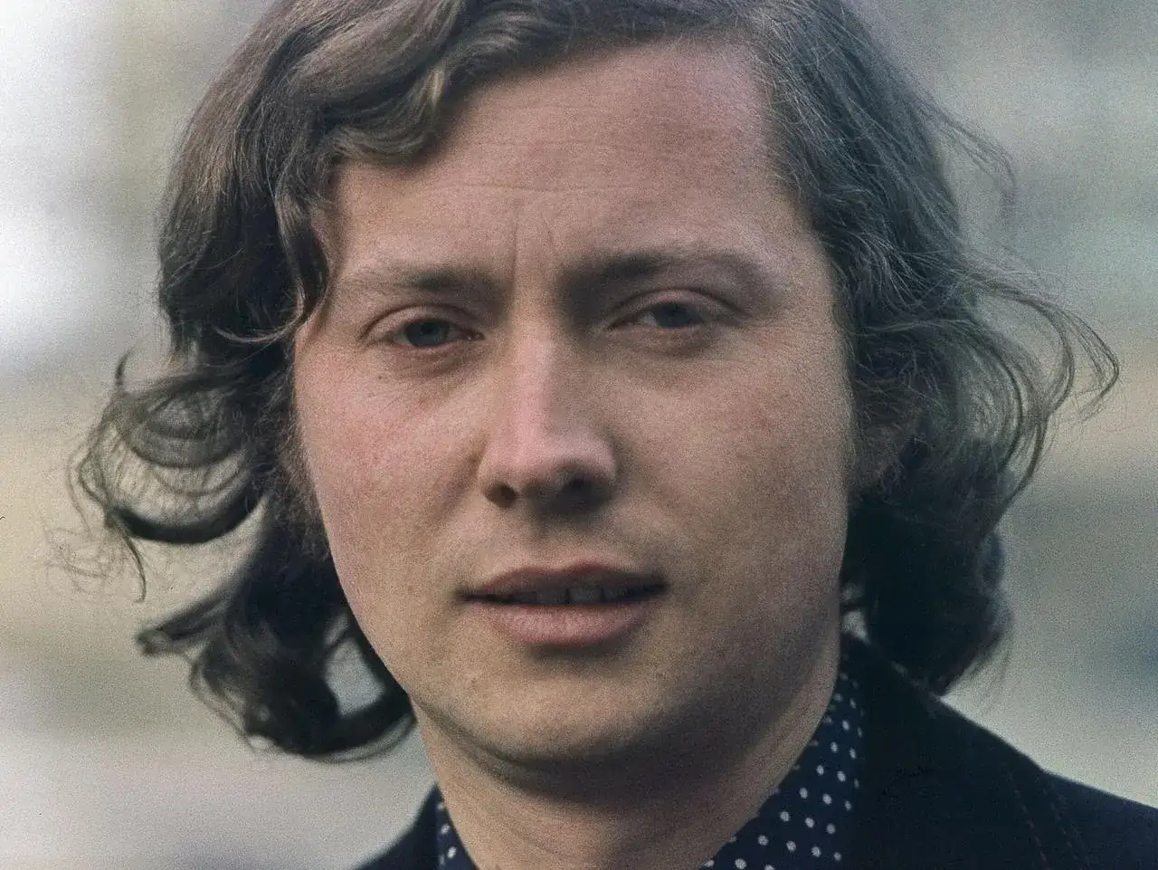 Portret mężczyzny z kręconymi włosami, który przypomina Marka Grechutę. Czy Marek Grechuta żyje?