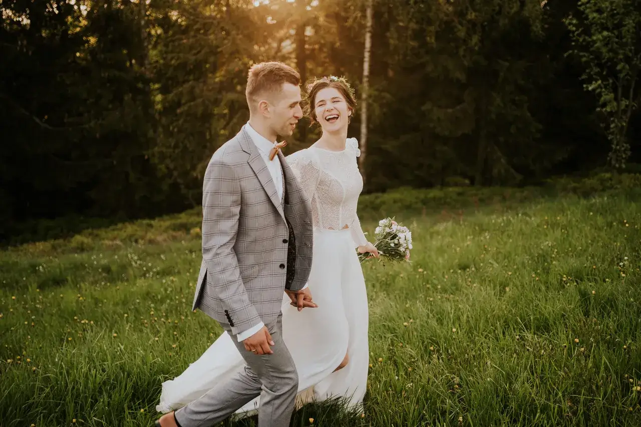 Szczęśliwa para młoda spaceruje po łące. Spóźnienie z rezerwacją fotografa może oznaczać, że nie uchwycimy takich chwil. 18 miesięcy to minimum.