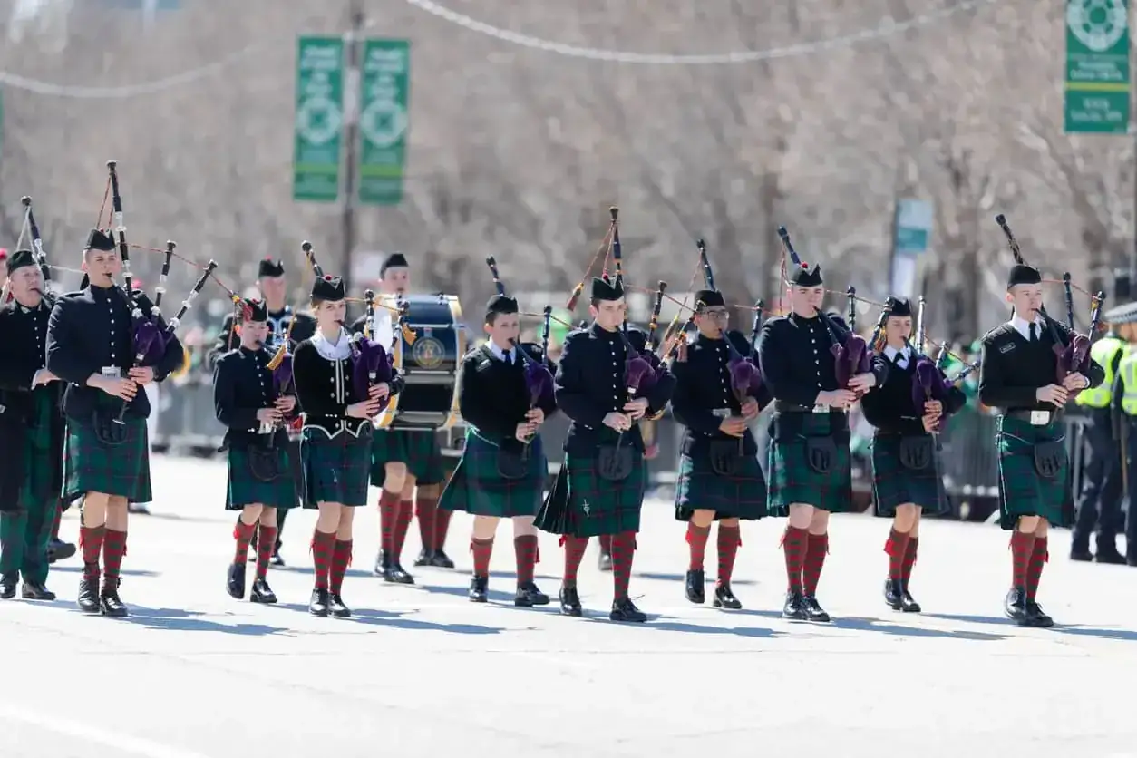 Orkiestra grająca na dudach w tradycyjnych szkockich strojach. Czy pod kiltem nosi się bieliznę? To pytanie pozostaje tajemnicą, gdy muzycy maszerują dumnie.