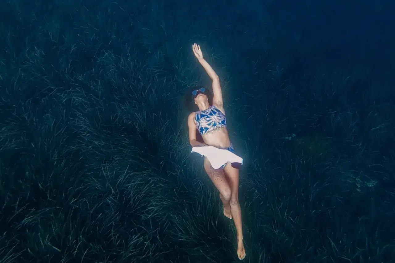 Kobieta w bikini unosi się na wodzie nad gęstą trawą morską. To jedno z najlepszych miejsc do nurkowania, gdzie można poczuć się jak ryba w wodzie.