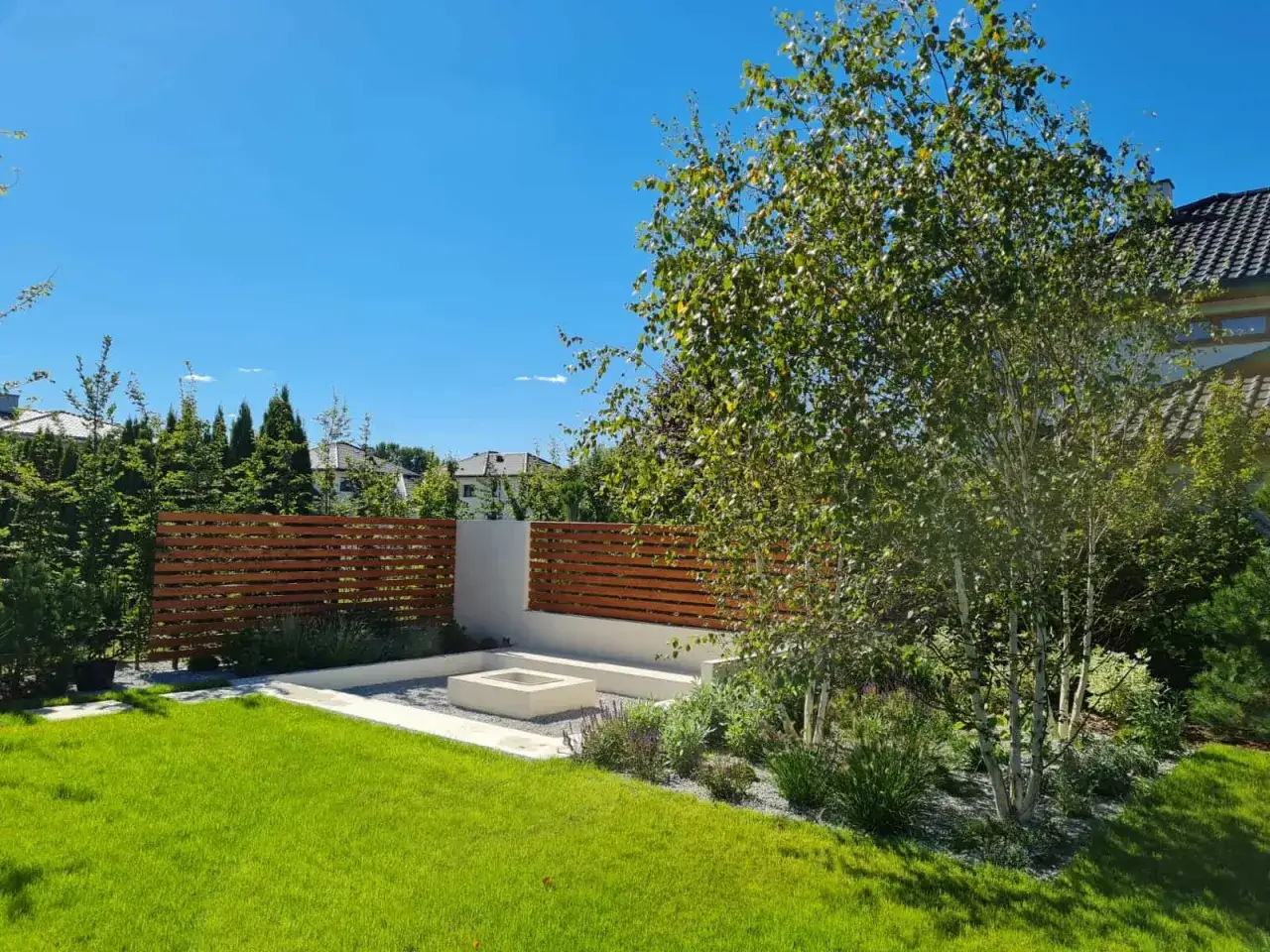 Nowoczesny ogr&oacute;d z paleniskiem i drewnianym płotem. Idealne miejsce, by zacząć planować ogr&oacute;d marzeń.