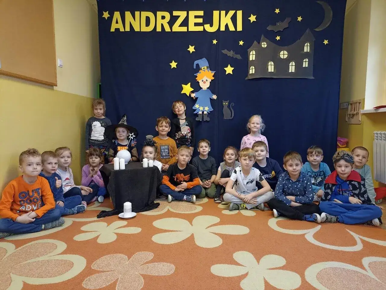 Dzieci w przedszkolu świętują andrzejki. W tle dekoracje z wr&oacute;żbami i zamkiem.