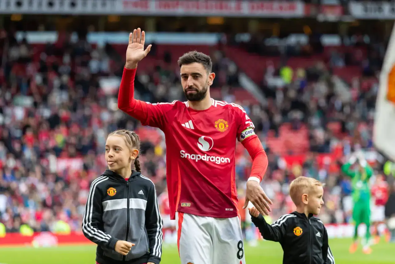 Bruno Fernandes, jeden z czerwonych diabł&oacute;w Manchester United, wita kibic&oacute;w z dziećmi u boku.