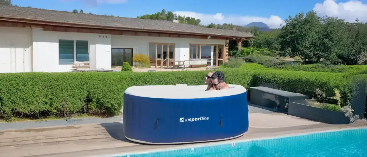 Para relaksu w ogrodzie: para cieszy się kąpielą w dmuchanym jacuzzi ogrodowym lay z spa, otoczonym zielenią i basenem.