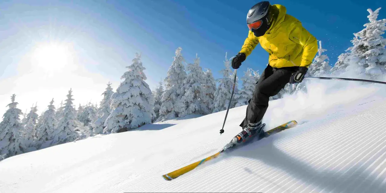 Narciarz w ż&oacute;łtej kurtce zjeżdża po stoku w Bukowinie Tatrzańskiej. Warto zobaczyć zimowe krajobrazy i poczuć adrenalinę!