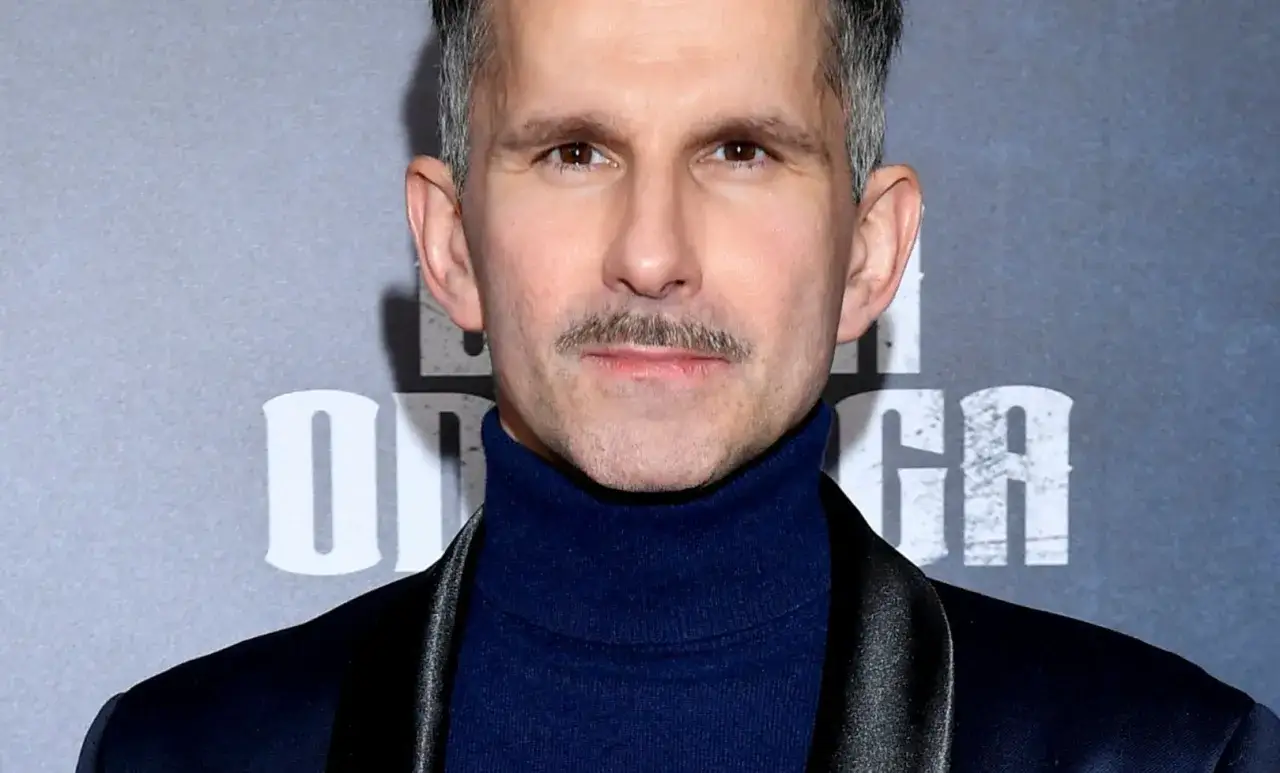 Aktor z wąsami w granatowym golfie i marynarce. Zastanawiasz się, ile zarabia aktor za dzień zdjęciowy?