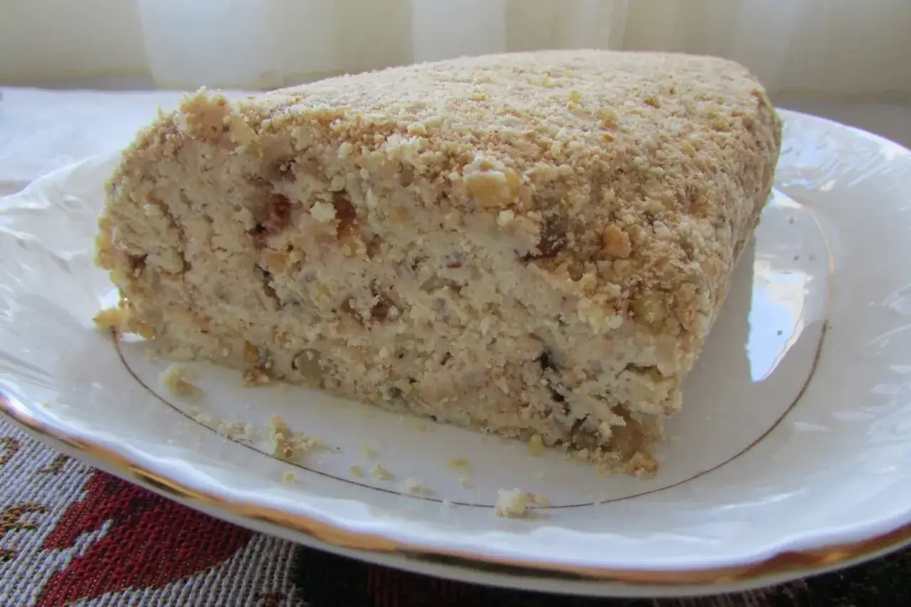 Kawałek pysznej, domowej rolady serowej z orzechami, posypanej okruszkami ciasta.