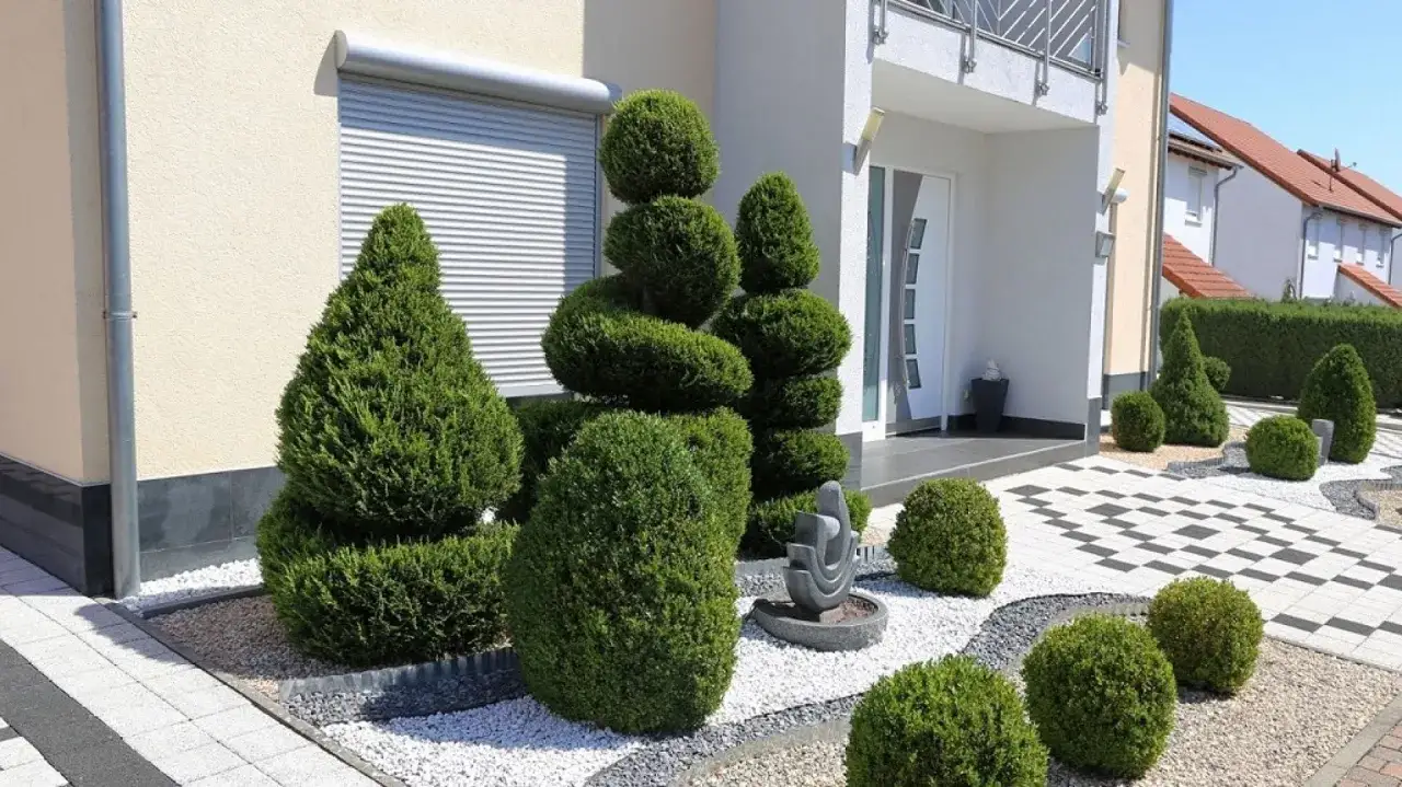 Piękne kostka brukowa wokół domu zdjecia. Krzewy formowane w kule i spirale, ozdobny kamień i biały grys tworzą nowoczesny ogród.