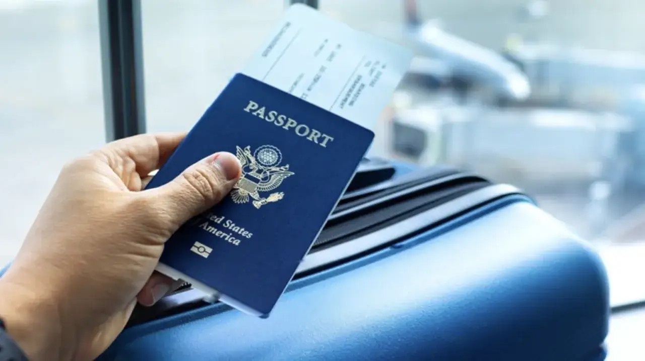 Ręka trzyma paszport USA i bilet lotniczy. Brak dowodu osobistego za granicą konsekwencje mogą być poważne.