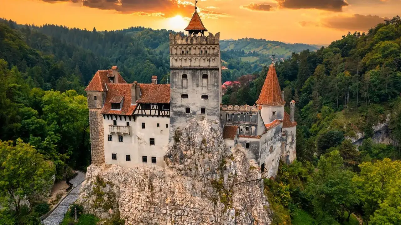 Zamek Drakuli, jedna z gł&oacute;wnych **transylwania atrakcje**, majestatycznie wznosi się na skale wśr&oacute;d zielonych wzg&oacute;rz o zachodzie słońca.