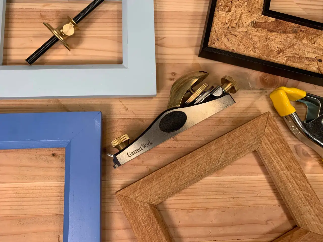 Narzędzia do tworzenia ramki do obrazu: strug, zacisk, kątownik i elementy ram.