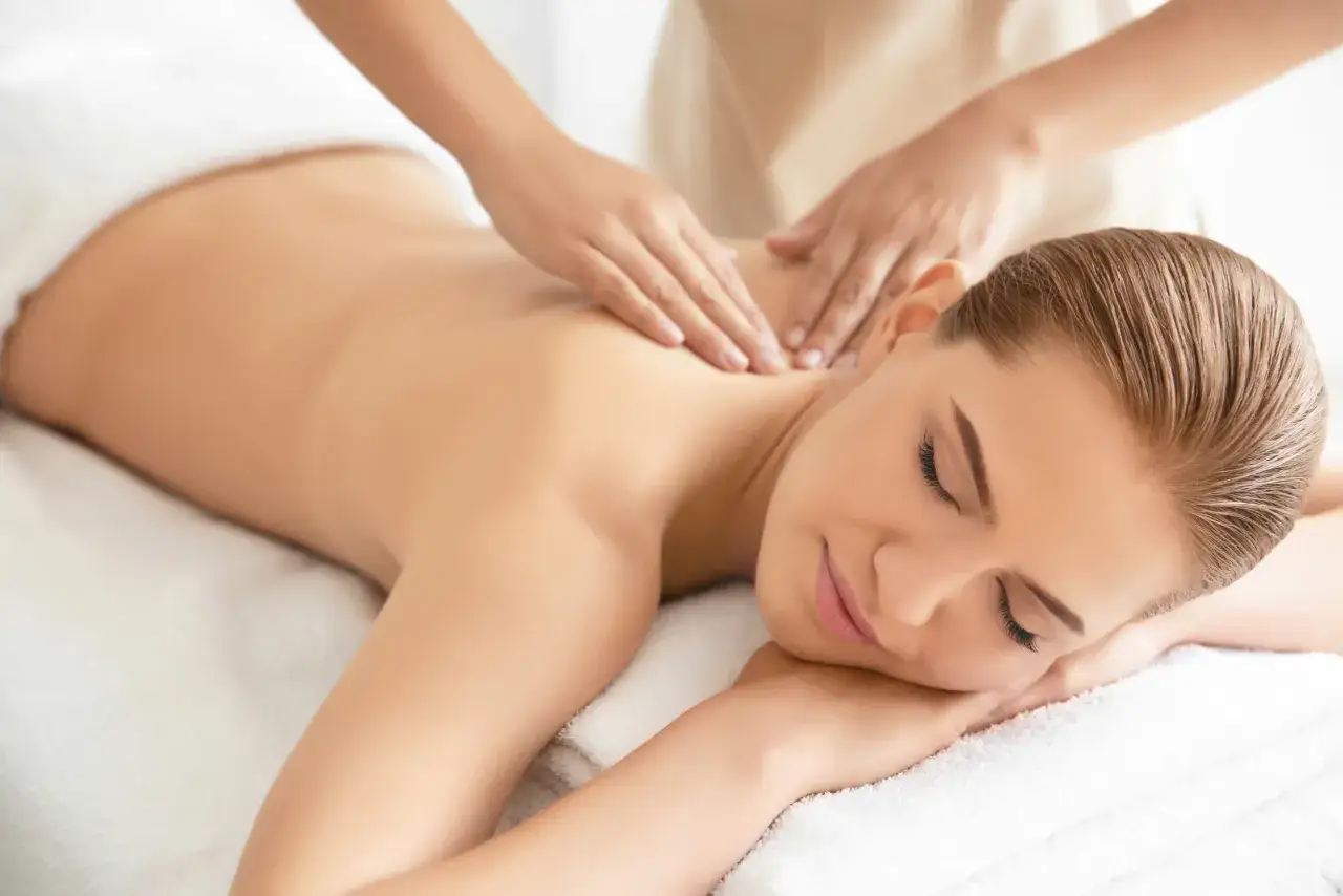 Kobieta zrelaksowana podczas masażu pleców. Idealny prezent: bon do spa na odprężenie.