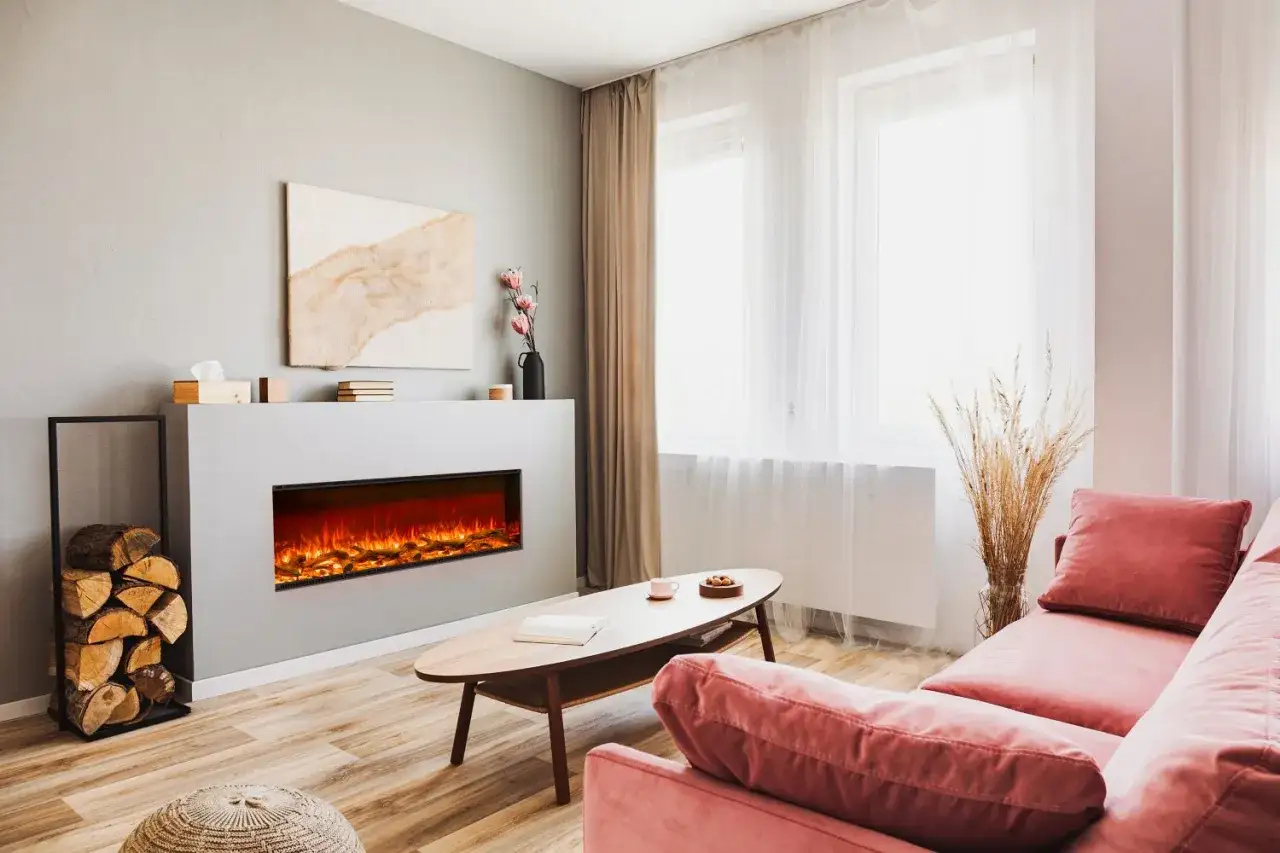 Nowoczesny salon z kominkiem elektrycznym do zabudowy, który tworzy przytulną atmosferę. Obok stos drewna.
