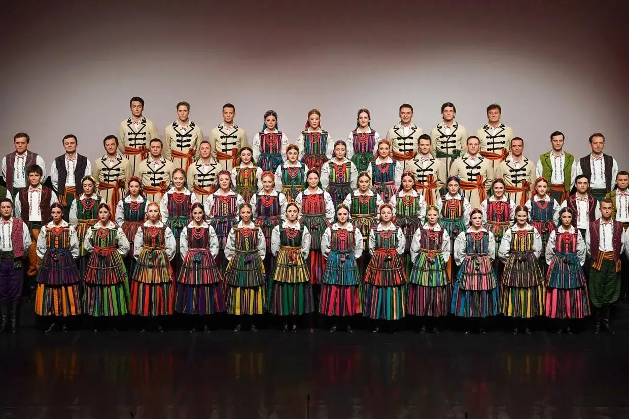 Zespół w barwnych strojach ludowych, gotowy do wykonania pieśni folk.