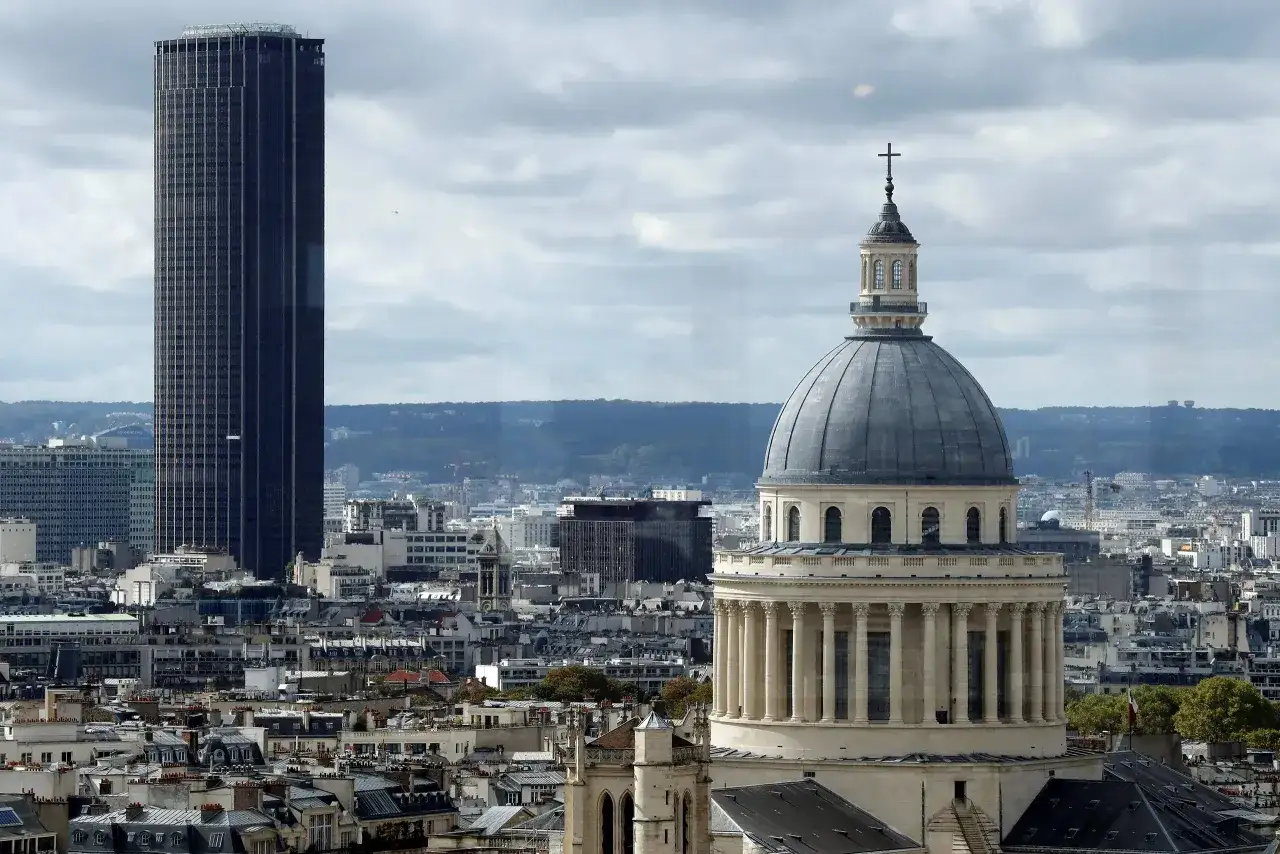 Panorama Paryża z dominującą kopułą Panteonu i wieżowcem Tour Montparnasse. Widok obejmuje dachy kamienic i zarys wzgórz w tle, ukazując 15 dzielnicę Paryża.