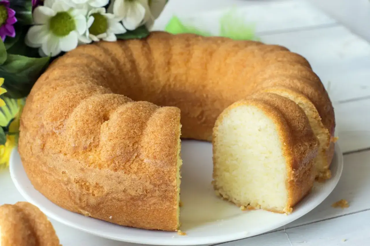 Puszysta babka piaskowa, kt&oacute;rą przygotowała Ania, gotuje się wesoło na talerzu. Obok bukiet kwiat&oacute;w.