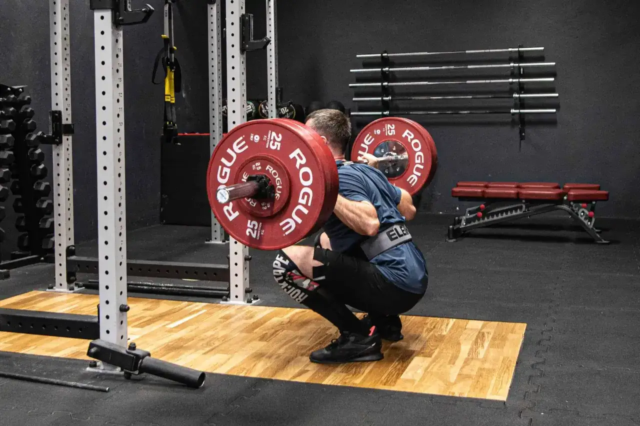 Trener CrossFit pomaga w technice przysiadu