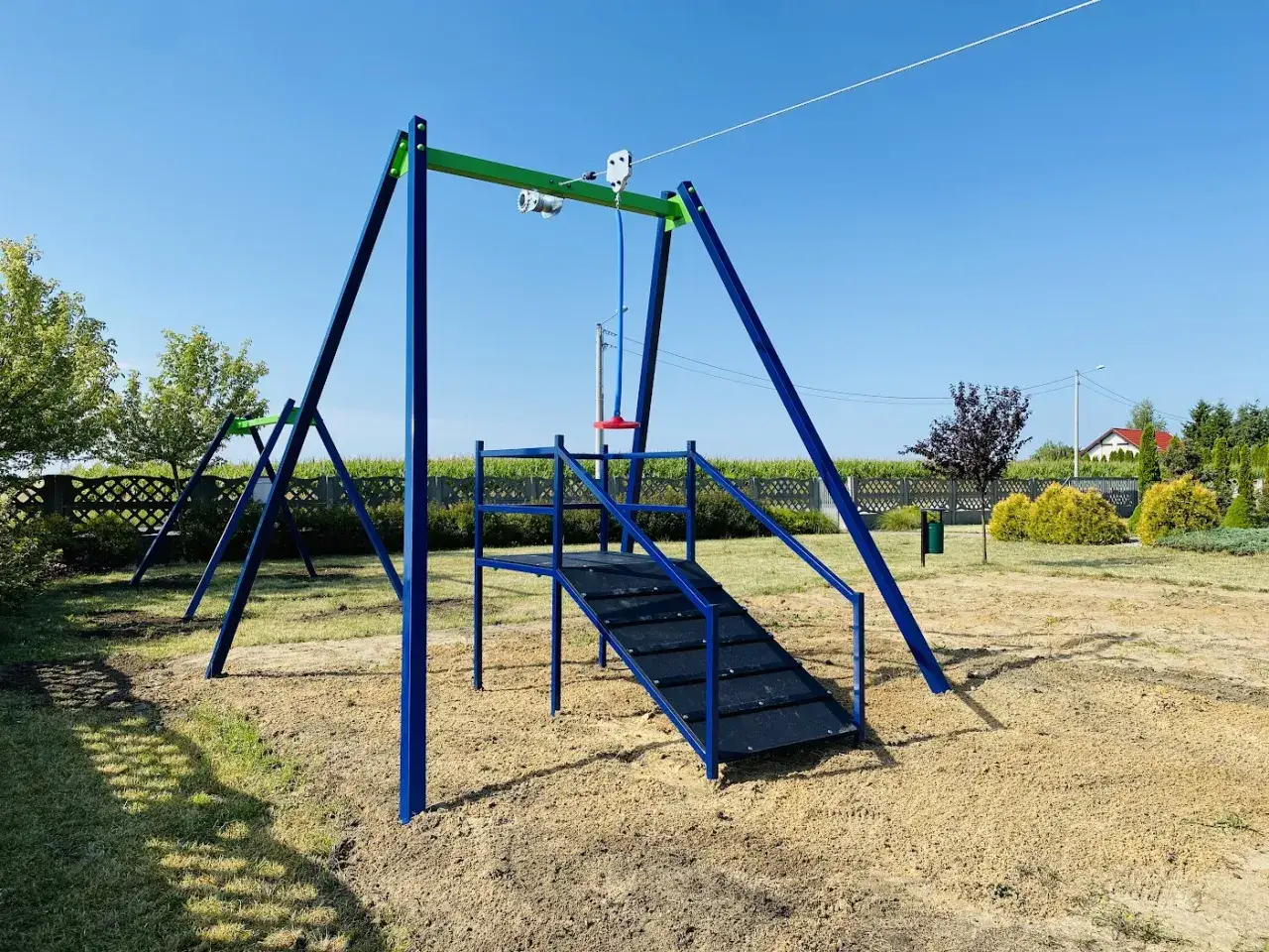 R&oacute;żnorodne urządzenia na placu zabaw: huśtawki, zjeżdżalnie, tyrolka, trampoliny ziemne