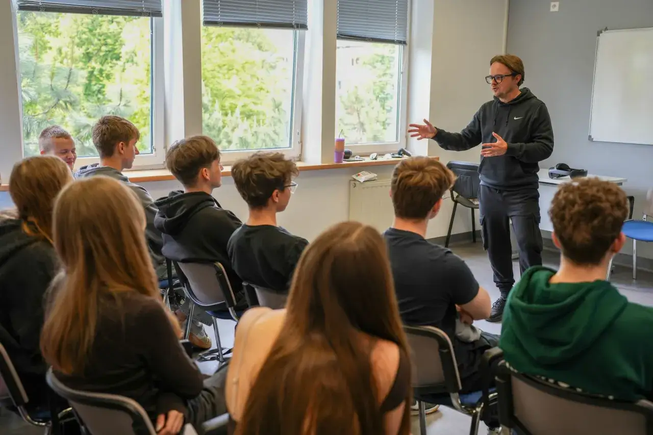 Nauczyciel z pasją opowiada grupie uczniów, jak zostać nauczycielem po administracji, inspirując ich do rozwoju.