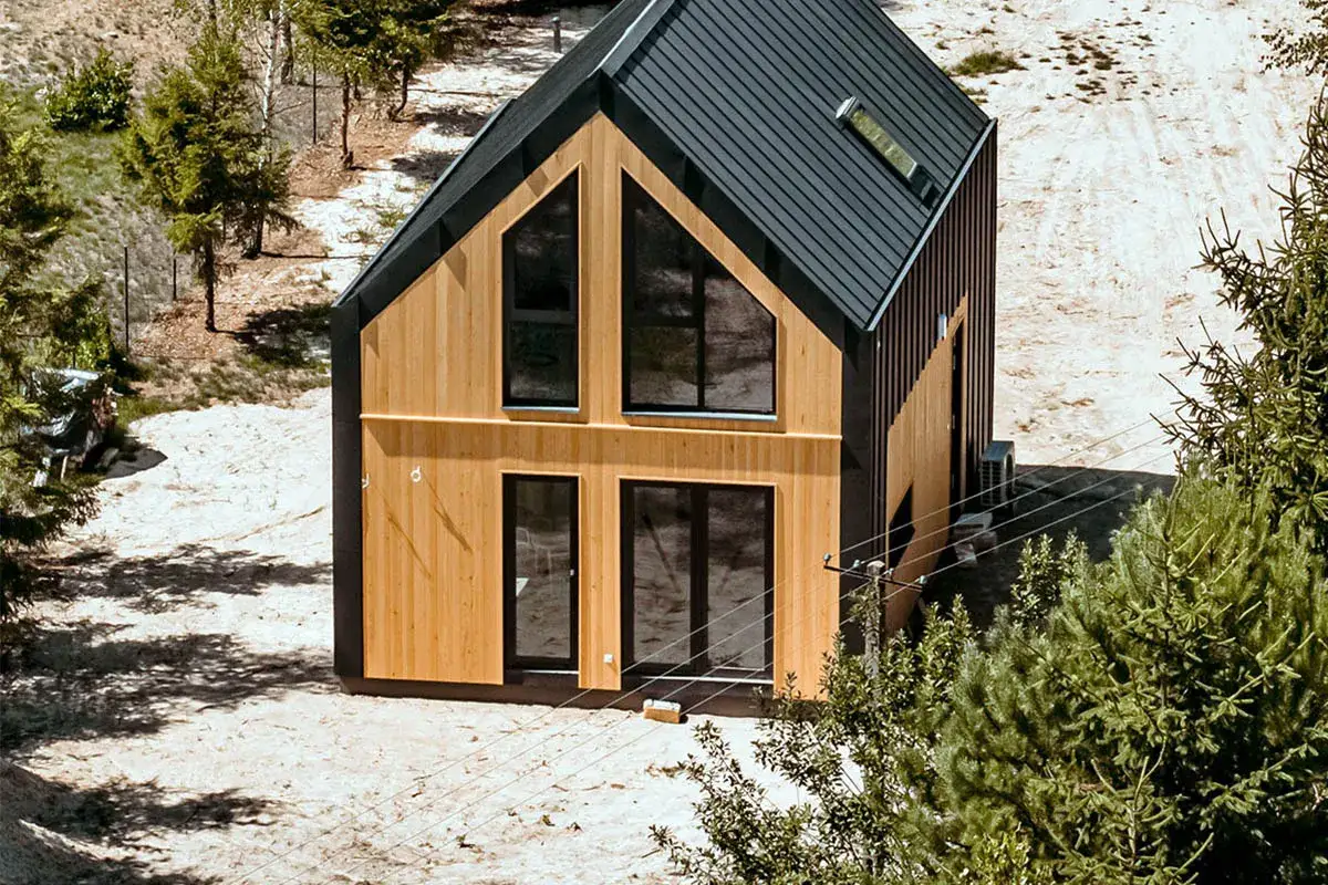 Nowoczesny dom modułowy z drewnianą elewacją i czarnym dachem. Szybka budowa domu modułowego to marzenie wielu.