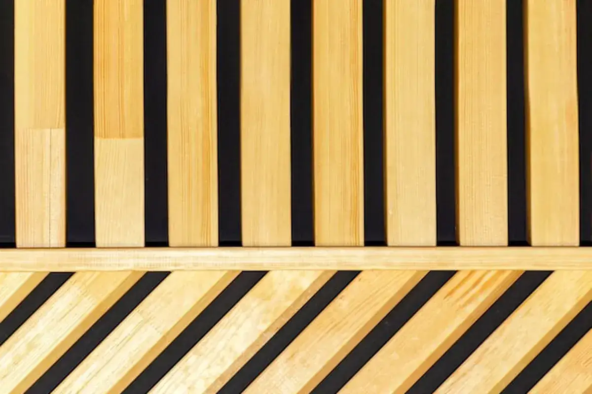 Jasne, oto opis:

Drewniane listwy na ścianie tworzą nowoczesną dekorację. Górna część to pionowe listwy, a dolna to ukośne, tworząc ciekawy wzór.