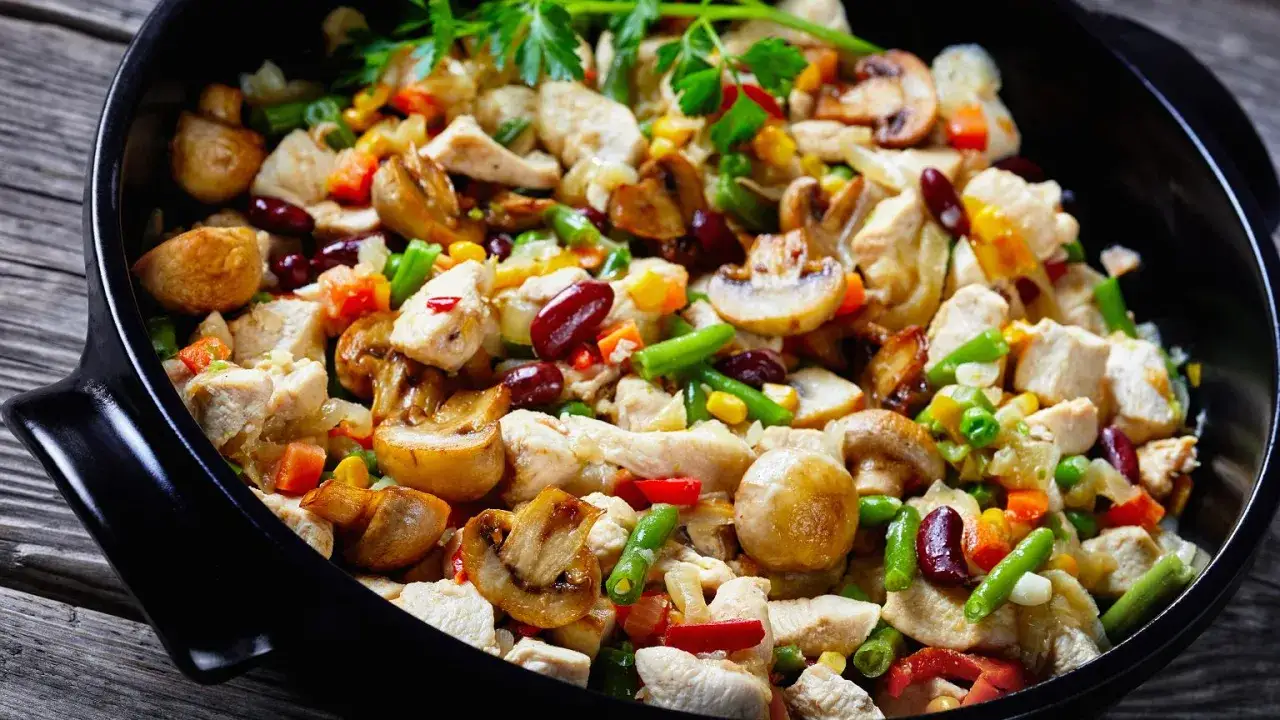 Pyszne danie z kurczakiem i mrożone warzywa w piekarniku: fasolka, kukurydza, marchewka, pieczarki i fasola czerwona.