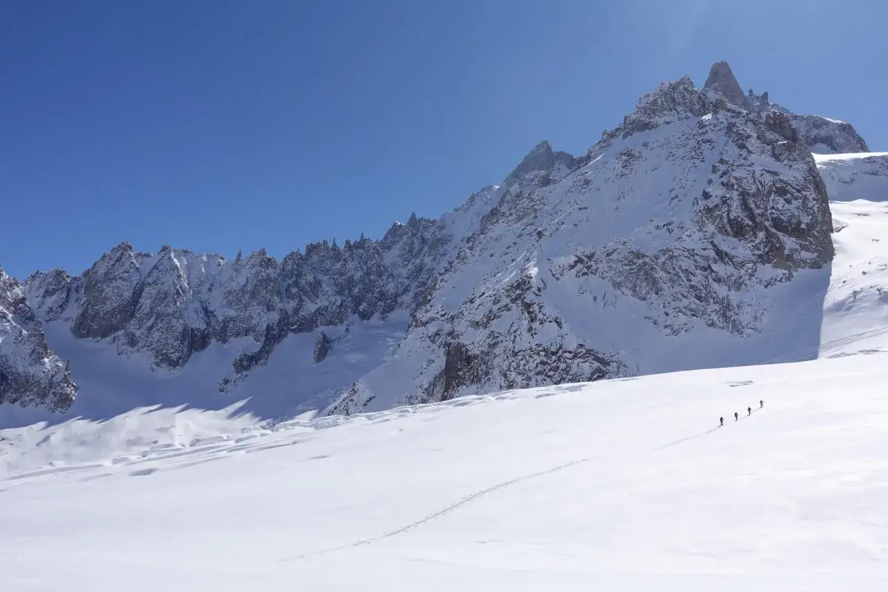 Grupa turystów wędruje po ośnieżonych zboczach w pobliżu Mont Blanc.