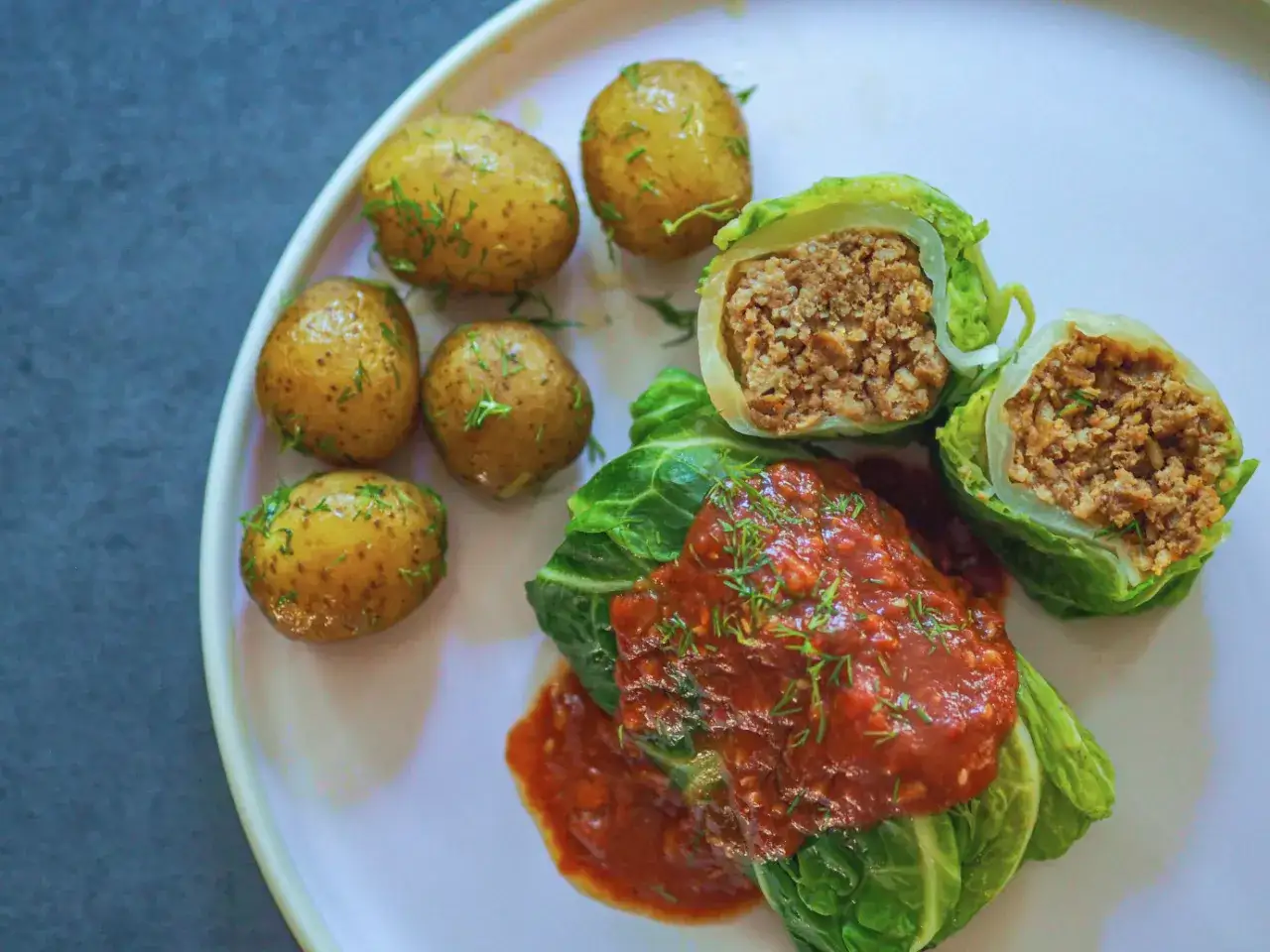 Gołąbki wegetariańskie z kaszą i warzywami, podane z sosem pomidorowym i ziemniaczkami. Pyszny spos&oacute;b, jak zrobić gołąbki wegetariańskie.