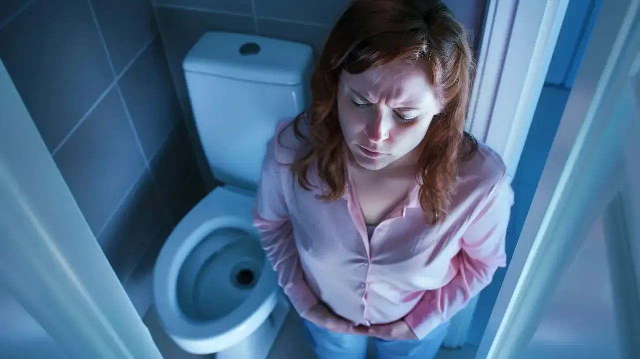 Kobieta z bólem brzucha siedzi na toalecie. Może banan na biegunkę pomoże?