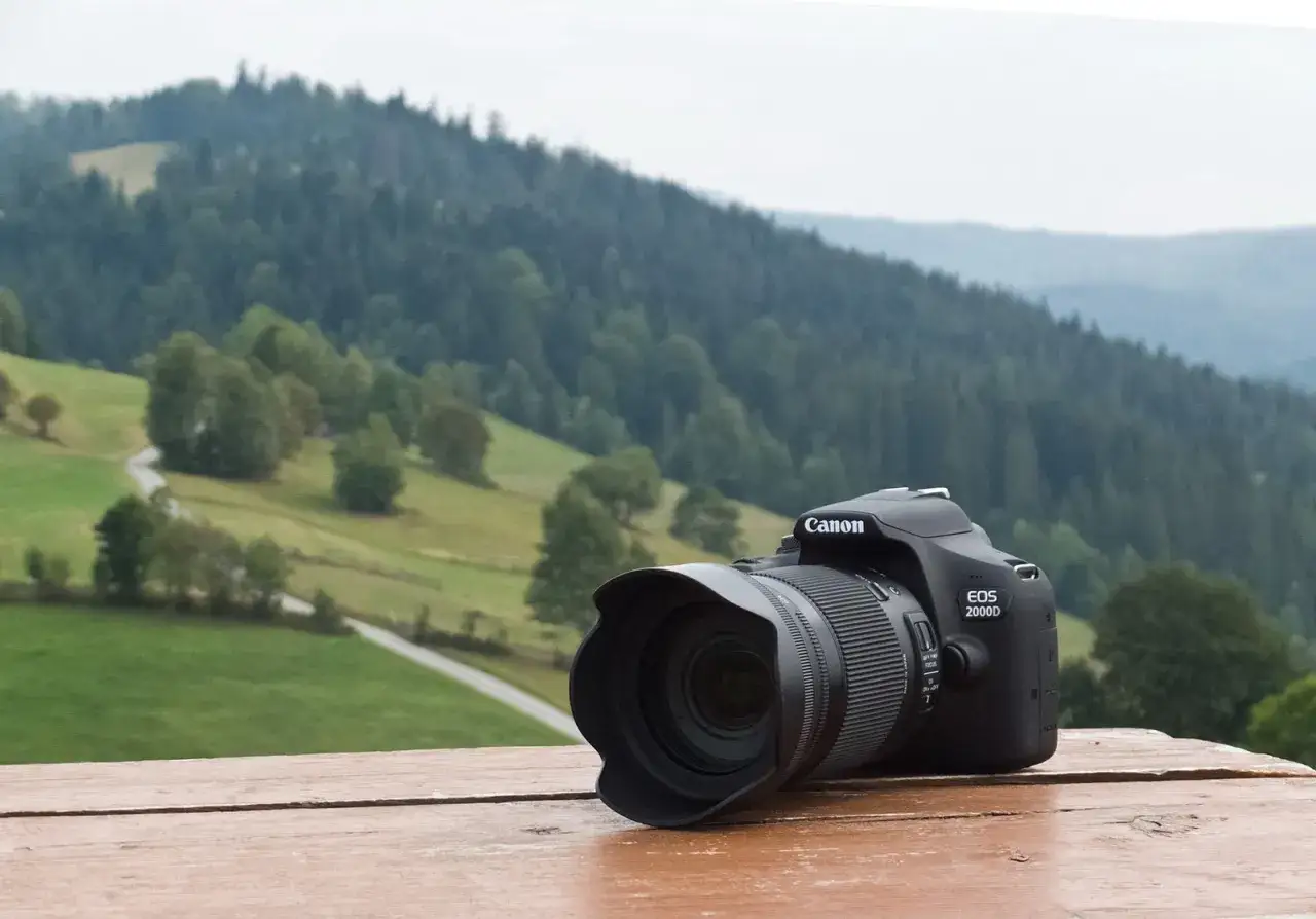 Canon EOS 2000D na tle g&oacute;rskiego krajobrazu. Aparat gotowy do uchwycenia piękna natury, choć jego wady i zalety warto rozważyć przed zakupem.