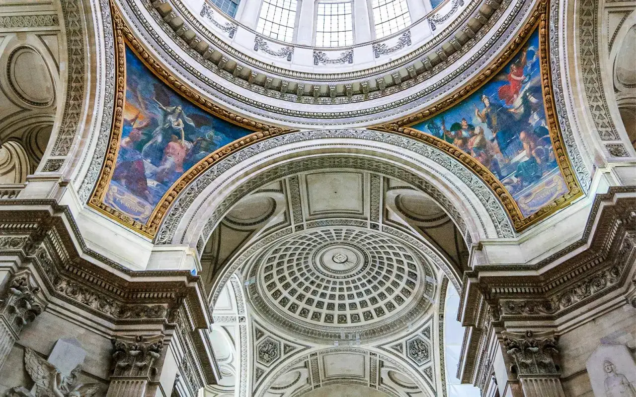 Wnętrze Panteonu w Paryżu. Monumentalna kopuła z malowidłami i bogatymi zdobieniami architektonicznymi.